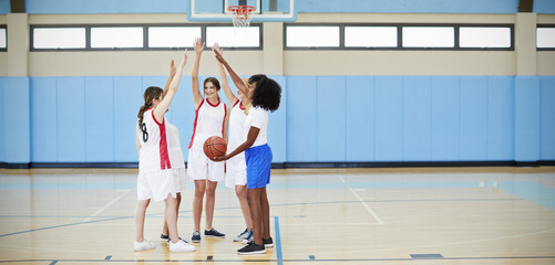 Obraz premium Female High School Basketball Players Joining Hands During Team Talk With Coach