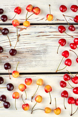 Arrangement of ripe cherries on wooden background. Mix of delicious cherries arranged in frame on wooden background with copy space. View from above.