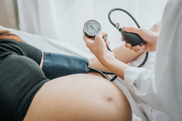 Doctor use sphygmomanometer checking blood pressure from pregnant woman - Powered by Adobe