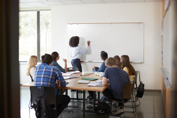 View Through Doorway Of High School Tutor At Whiteboard Teaching Maths Class