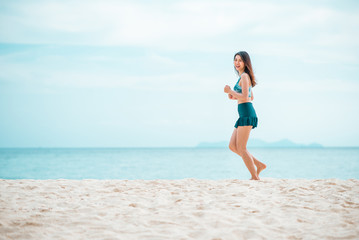Fototapeta na wymiar Happy Asian woman jogging on the beach in the morning