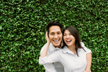 Happy Asian couple in love smiling while hug each other outdoor