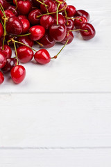 Obraz na płótnie Canvas Heap of ripe red cherries and copy space. Pile of berries with water drops on white background and space for text, vertical image.