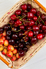 Basket of ripe cherries, top view. Sweet assorted cherries in wicker basket. Natural tasty fruit.