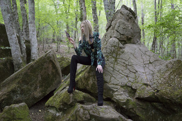 Fashion Model Girl on the Rock in the green summer forest