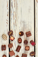 Assorted chocolate candies and copy space. Mix of chocolate sweets on wooden background and space for text.