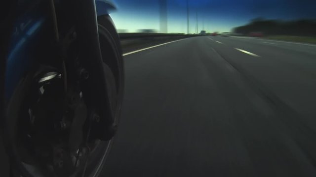 Crazy camera moves around motorbike speeding down a highway. Camera moves inches from wheels and up over the bike.