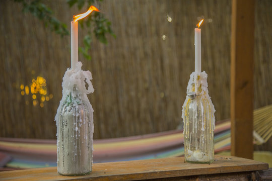 image of two bottles completely covered by candles wax with two burning candles