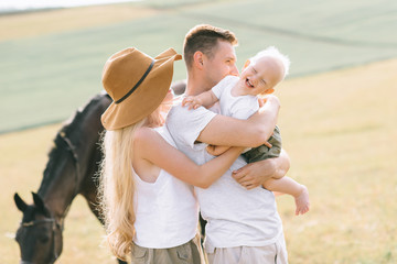 A young family have a fun in the field. Parents and child with a horse