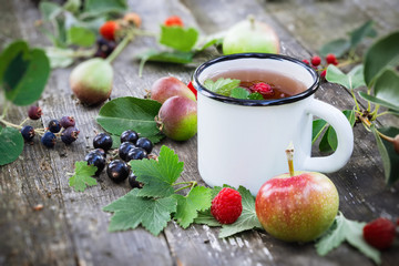 Enameled cup of fruit tea with apples, pears, raspberries and black currant berries.