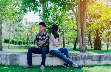 Bad relationship concept. Man and woman in disagreement. Young couple after quarrel in the park. Filtered image.