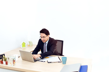 Young businessman working with laptop and office Supplies.He looking smiling.Copy space.