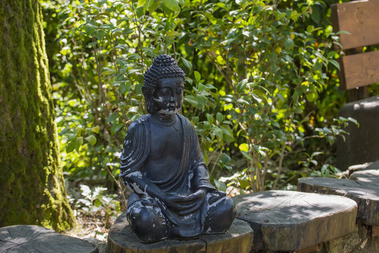 horizontal image of a black stone statue depicting Buddha