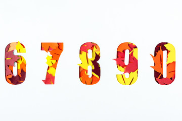 Numbers 6, 7, 8, 9, 0 text with paper cut maple leaves. Top view.