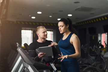 Fitness coach helps woman on elliptical trainer