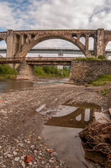 Carpathian stone aqueduct reflected in water 