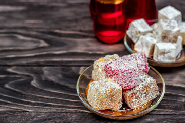 Traditional oriental sweets and traditional Turkish tea on a dark wooden background. Turkish desert-Rahat locum.