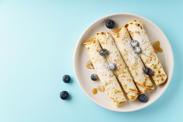 Rolled pancakes with blueberry on blue background with text space