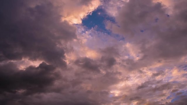 Video recording dense pink cumulus clouds floating along the blue evening sky, illuminated by the rays of the sun