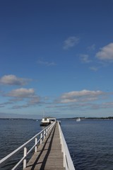 Fototapeta na wymiar idyllische Seebrücke mit Segelboot an der Kieler Förde 