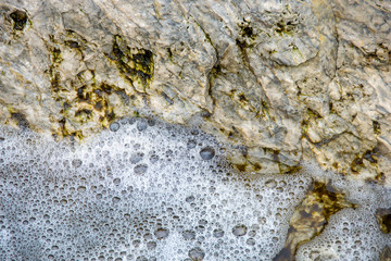 close up of white water bubbles with rock surface background