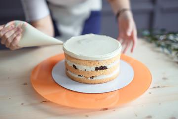 confectioner in a white apron on a dark background with a cake