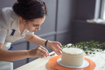 confectioner in a white apron on a dark background with a cupcake