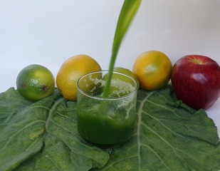Freshly blended green smoothie in a glass on white background. Template for detox recipe, copy space. Vegetarian food.  Green juice with kale, orange, apple and lemon