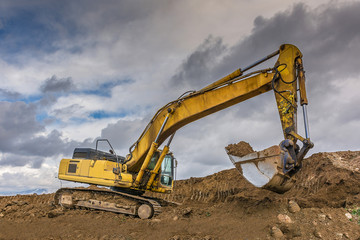 Fototapeta na wymiar Excavator loading earth to perform works of settlement of a road