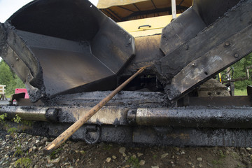 Construction workers during road works with asphalt pavement machine