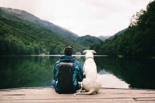 Man sitting with a dog on dock at the lake