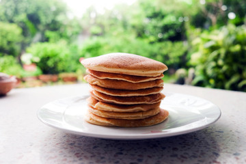 Stack of delicious pancakes on plate on the table.