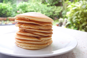 Stack of delicious pancakes on plate on the table.