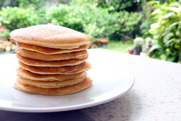 Stack of delicious pancakes on plate on the table.