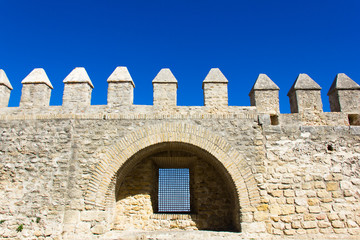 Fototapeta na wymiar Front wall of castle tower with window inside arc structure and intense blue sky on the background in Vejer white town, Andalusia. Protection, security, defense concepts