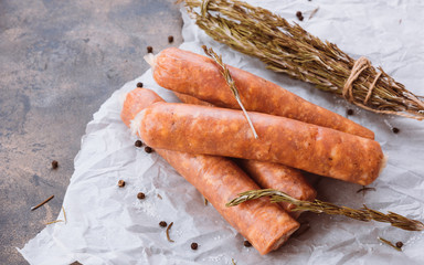 Raw sausages on a dark rustic metallic background. Meat sausages with spices on a baking paper. Copy space