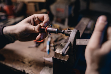Man winds an induction coil made of copper wire for tattoo machines.