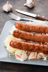 Grilled sausages with sauerkraut. Bavarian fried sausages with mashed potatoes and cabbage on a plate. Top view