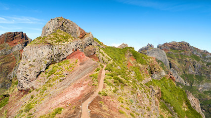 Fototapeta na wymiar Colorful mountain ridge path with volcanic formation in background, Pico do Arieiro, Madeira, Portugal