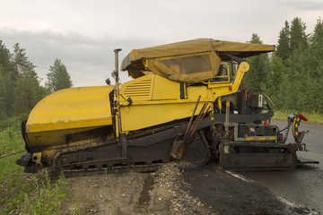Construction workers during road works with asphalt pavement machine