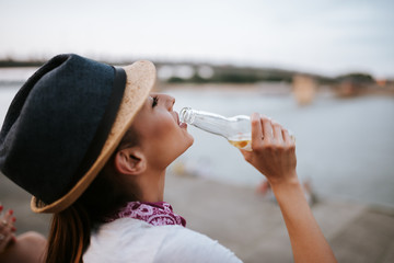 Close-up image of beautiful girl drinking from a bottle while sitting outdoors.