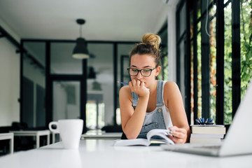 Hpister girl in suspenders pants studying at group study room.
