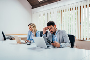 Two business people working on laptops in coworking office.