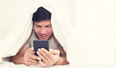 man sitting on bed and watch movie on phone at home in the bedroom