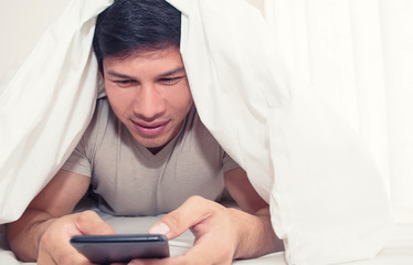 man sitting on bed and watch movie on phone at home in the bedroom