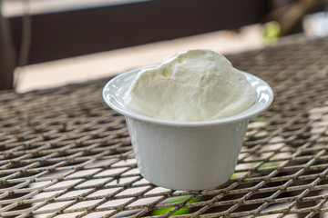 Whipping cream in the white cup on the metal table