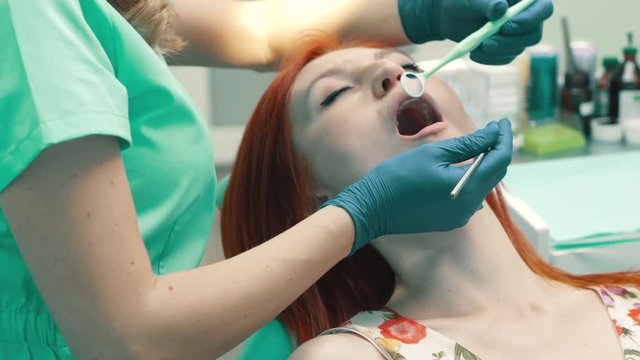 female dentist examines oral cavity of patient, close up