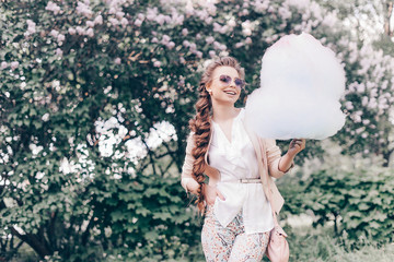 Portrait of a Smiling Beautiful Lady in Sunglasses Holding Cotton Candy at Park and Happily Looking...