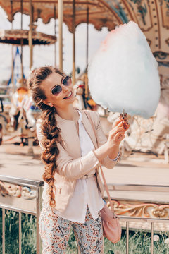 Portrait of a Smiling Beautiful Lady in Sunglasses Holding Cotton Candy at Park and Happily Looking in Camera.