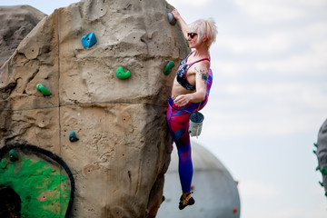 Photo of young girl exercising on boulder for rock climbing against sky background with clouds